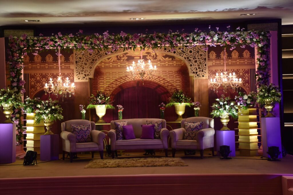 A wedding stage adorned with elegant purple and gold flowers, set for a celebration in Delhi.