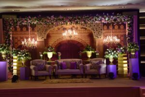 A wedding stage adorned with elegant purple and gold flowers, set for a celebration in Delhi.